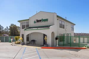 The Sentry Storage Solutions facility has a two-story beige stucco building with green trim, a gated entrance, and security fencing.