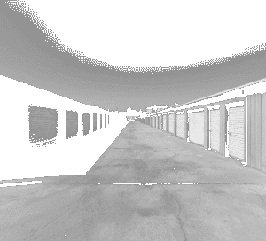 Black and white photo of a long driveway lined with self-storage units featuring metal roll-up doors on both sides at Sentry Storage Solutions.