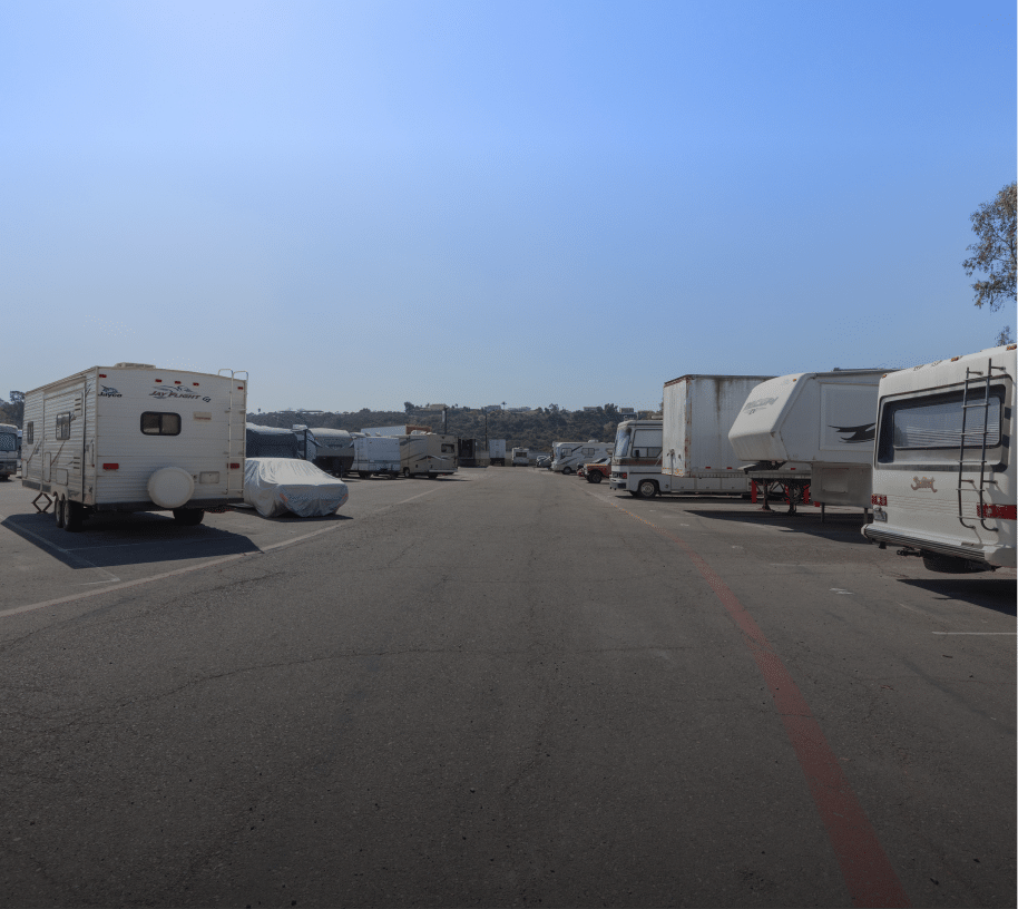 Wide view of an outdoor RV storage lot at Sentry Storage Solutions with multiple parked recreational vehicles, travel trailers, and motorhomes lined up on both sides of a paved driveway.